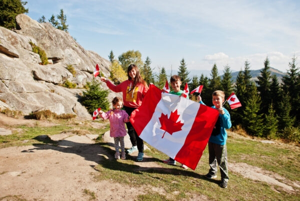 happy canada day family mother with three kids hold large canadian flag celebration mountains